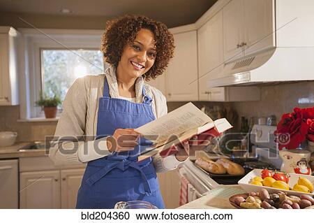 Stock Image - Mixed race woman baking in kitchen. Fotosearch