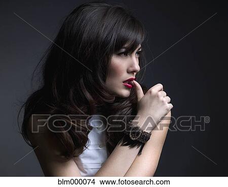 Picture - Mixed Race woman biting on thumb. Fotosearch