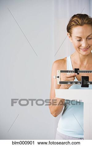 Mixed race woman checking weight on scale View Large Photo Image Stock Image - Mixed race woman checking weight on scale. Fotosearch