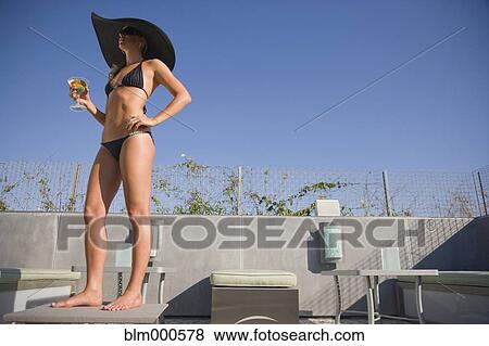 Stock Photo - Mixed race woman drinking cocktails poolside. Fotosearch