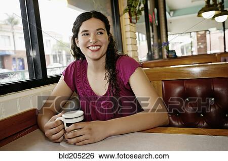 Stock Photograph - Mixed race woman having coffee in restaurant. Fotosearch