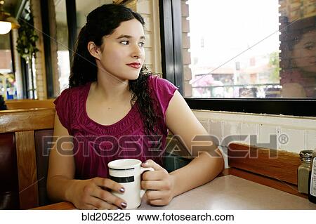 Stock Photography - Mixed race woman having coffee in restaurant. Fotosearch