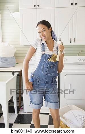 Mixed race woman holding hammer in laundry room View Large Photo Image Stock Image - Mixed race woman holding hammer in laundry room. Fotosearch