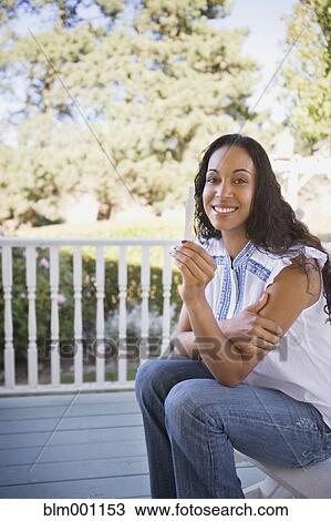 Stock Image - Mixed race woman holding pregnancy test. Fotosearch