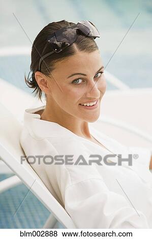 Mixed race woman in sunglasses sitting in lounge chair View Large Photo Image Stock Photo - Mixed race woman in sunglasses sitting in lounge chair. Fotosearch