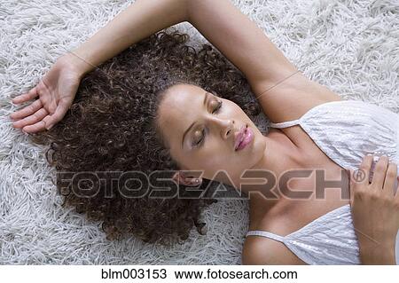 Stock Image - Mixed race woman laying on floor asleep. Fotosearch