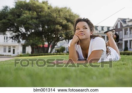 Picture - Mixed race woman laying on grass. Fotosearch