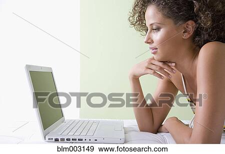 Mixed race woman laying on sofa using laptop View Large Photo Image Stock Photo - Mixed race woman laying on sofa using laptop. Fotosearch