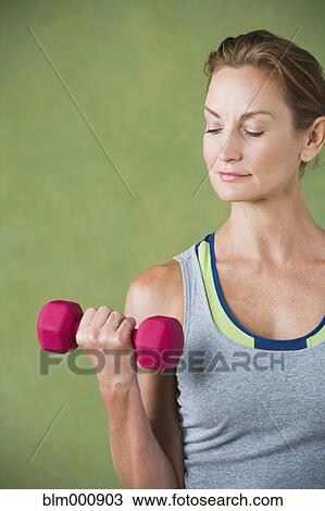 Stock Image - Mixed race woman lifting hand weight. Fotosearch