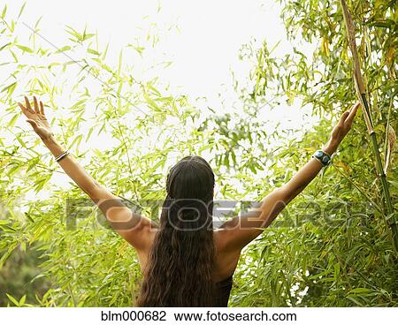 Stock Image - Mixed race woman outdoors with arms raised. Fotosearch