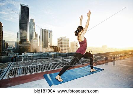 Mixed race woman practicing yoga on urban rooftop View Large Photo Image Picture - Mixed race woman practicing yoga on urban rooftop. Fotosearch