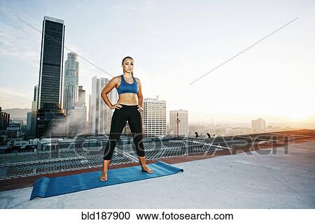 Stock Image - Mixed race woman practicing yoga on urban rooftop. Fotosearch