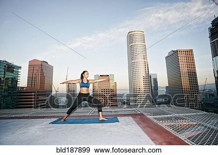 Stock Photo - Mixed race woman practicing yoga on urban rooftop. Fotosearch