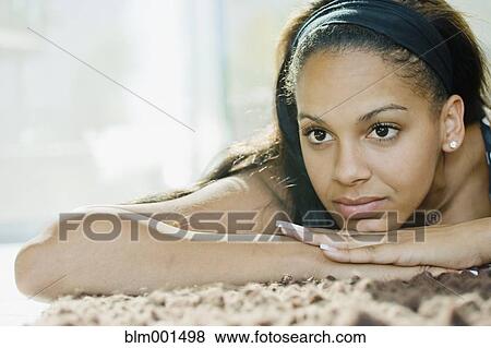 Stock Photo - Mixed race woman relaxing on rug. Fotosearch