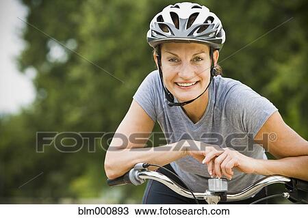 Stock Image - Mixed race woman riding bicycle. Fotosearch