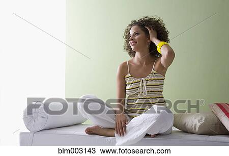 Mixed race woman sitting cross-legged on sofa View Large Photo Image Stock Image - Mixed race woman sitting cross-legged on sofa. Fotosearch