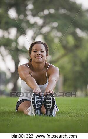 Mixed race woman sitting on grass stretching View Large Photo Image Stock Image - Mixed race woman sitting on grass stretching. Fotosearch
