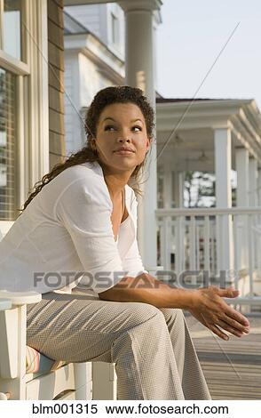 Stock Photography - Mixed race woman sitting on porch. Fotosearch