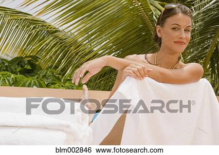 Stock Photograph - Mixed race woman sunbathing on lounge chair. Fotosearch