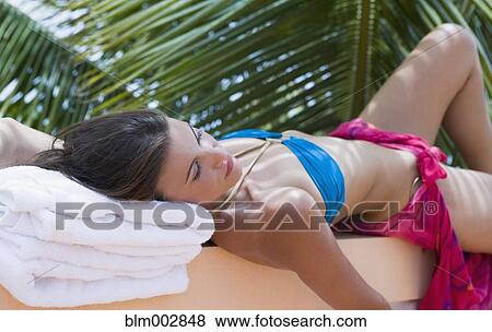 Stock Photo - Mixed race woman sunbathing on wall. Fotosearch