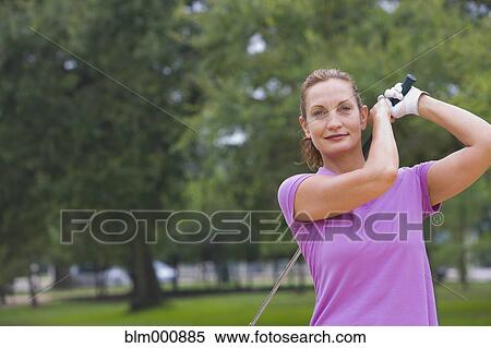 Stock Photography - Mixed race woman swinging golf club. Fotosearch