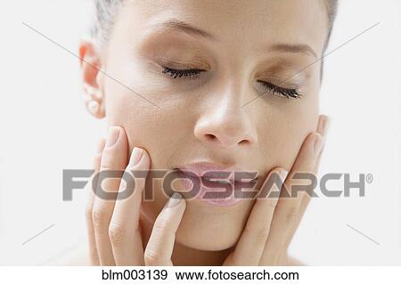 Stock Photo - Mixed race woman with head in hands and eyes closed. Fotosearch