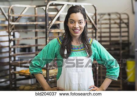 Stock Photo - Mixed race woman working in bakery kitchen. Fotosearch