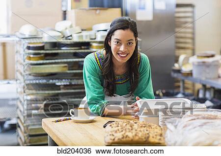 Stock Photograph - Mixed race woman working in bakery kitchen. Fotosearch