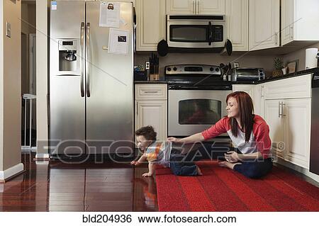 Mother and baby playing in kitchen View Large Photo Image Stock Photograph - Mother and baby playing in kitchen. Fotosearch
