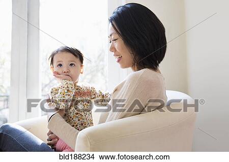 Picture - Mother and daughter hugging on sofa. Fotosearch