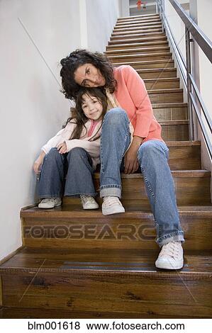 Stock Photo - Mother and daughter hugging on stairs indoors. Fotosearch