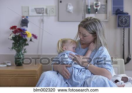 Stock Image - Mother and daughter in hospital gowns. Fotosearch