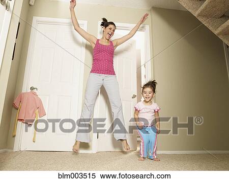 Stock Photography - Mother and daughter jumping in house. Fotosearch