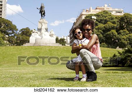 Stock Image - Mother and daughter smiling in park. Fotosearch