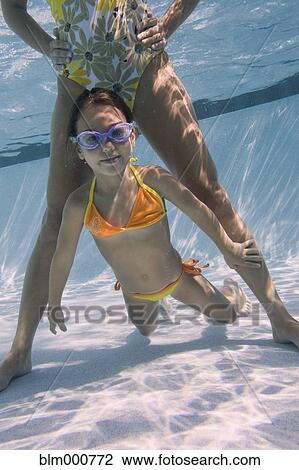Stock Image - Mother and daughter swimming in swimming pool. Fotosearch