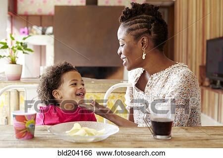 Stock Photograph - Mother and daughter talking at breakfast table. Fotosearch