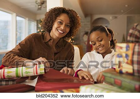Stock Image - Mother and daughter wrapping Christmas presents. Fotosearch