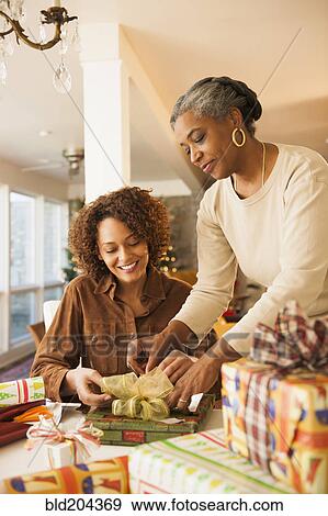 Stock Photo - Mother and daughter wrapping Christmas presents. Fotosearch