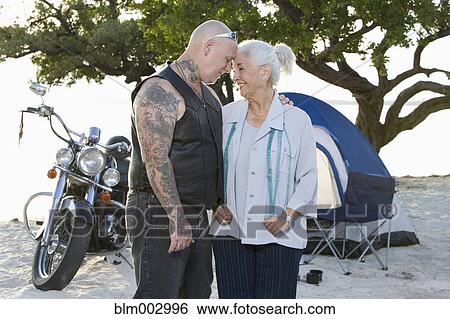 Stock Photograph - Mother and tattooed son camping at the beach. Fotosearch