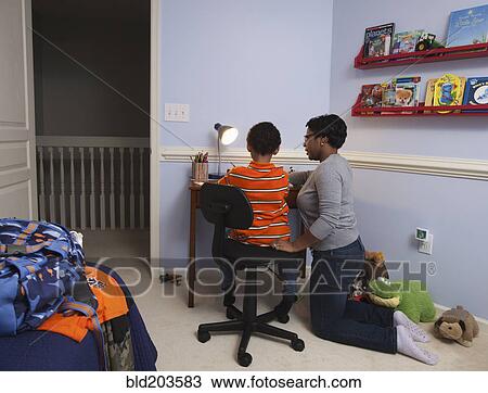 Stock Image - Mother helping son with homework. Fotosearch