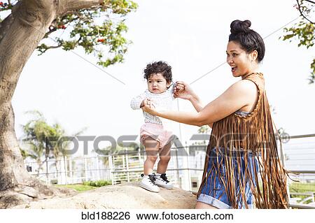 Stock Photograph - Mother playing with baby son in park. Fotosearch