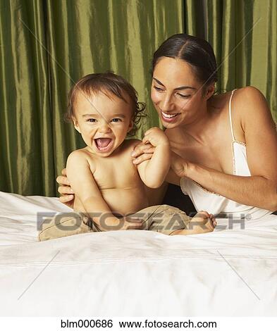 Stock Photograph - Mother playing with son on bed. Fotosearch