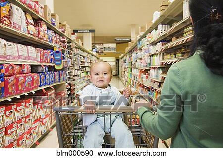 Stock Image - Mother shopping in grocery store with baby. Fotosearch
