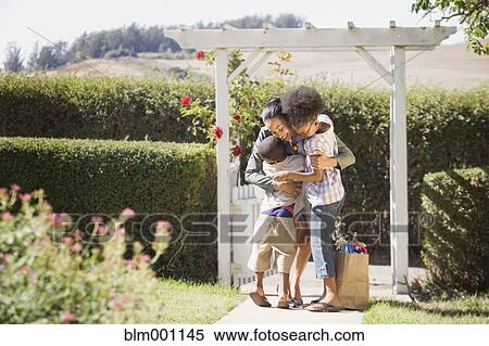 Stock Photography - Mother with groceries hugging children. Fotosearch
