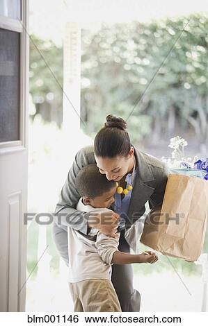 Stock Photograph - Mother with groceries hugging son. Fotosearch