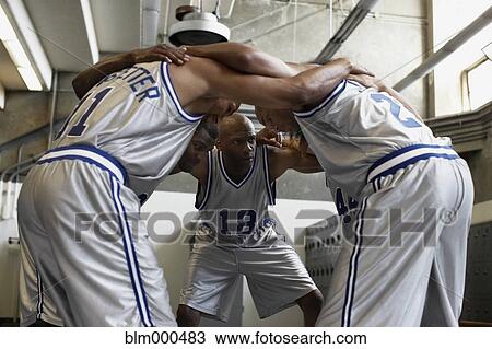 Stock Image - Multi-ethnic basketball players huddling in locker room. Fotosearch