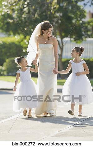 Stock Image - Multi-ethnic bride holding hands with flower girls. Fotosearch