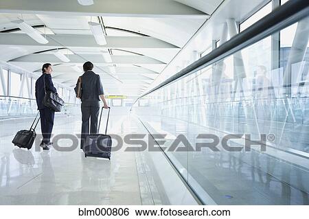 Stock Photograph - Multi-ethnic business people walking in airport. Fotosearch