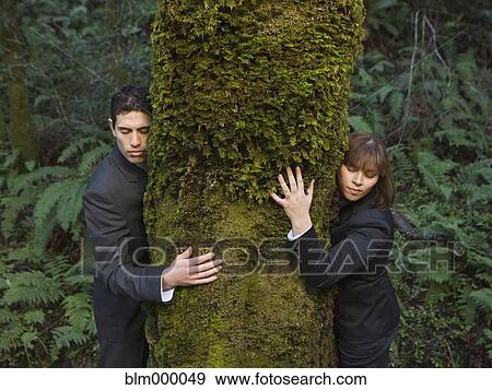 Multi-ethnic businesspeople hugging tree View Large Photo Image Stock Photo - Multi-ethnic businesspeople hugging tree. Fotosearch