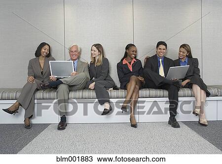 Stock Image - Multi-ethnic businesspeople working on bench. Fotosearch